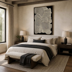 Wood framed ribbed abstract artwork above a cream upholstered bed with a dark throw.