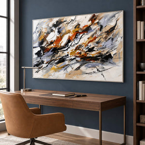 Hand-painted abstract artwork with black gestures and rust, ochre, ivory, and gray layers, displayed in a home office in a silver frame.