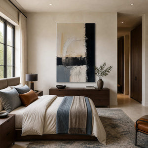 White-framed neutral and blue abstract art above a wood dresser beside a bed with a blue throw.