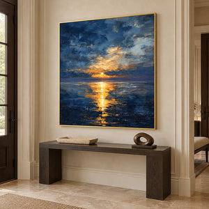 Gold-toned framed seascape above a dark console near a tall window and doorway.