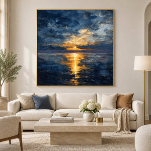 Blue seascape with a golden reflection above a cream sofa and pale stone coffee table.