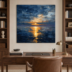 Sunlit sea painting behind a wood desk and brown chair between tall bookshelves.