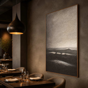 Textured gray shoreline artwork displayed in a boutique dining room.