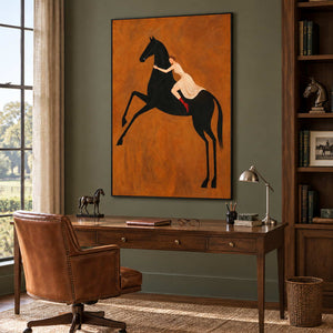 Wild at Heart in a black frame above a wood desk with a small horse sculpture and brown leather chair.