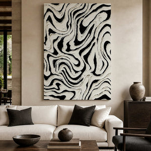 Frameless black and white abstract artwork with flowing ridges above a cream living room sofa.