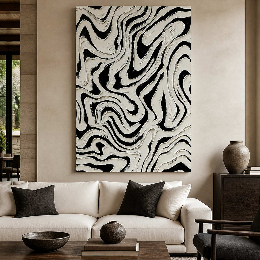 Frameless black and white abstract artwork with flowing ridges above a cream living room sofa.