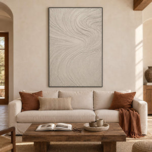 Ivory relief painting with fine flowing wave-like ridges in a black frame in a living room.