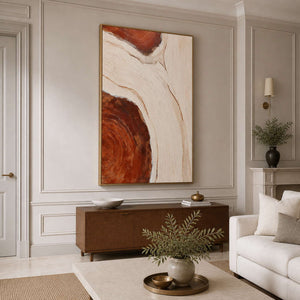 Gold framed rust and cream artwork above a walnut cabinet in a sitting room.