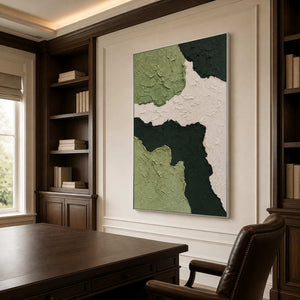 Silver framed textured green artwork behind a walnut desk between dark bookshelves.