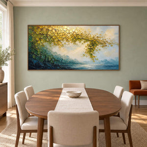 Golden foliage and misty blue water landscape painting in a brown wood frame in a dining room.
