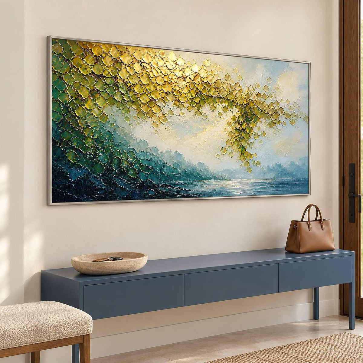Golden foliage and misty blue water landscape painting in a silver frame in an entryway.