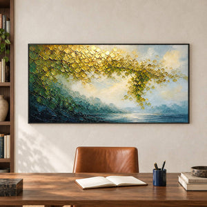Golden foliage and misty blue water landscape painting in a black frame in a home office.