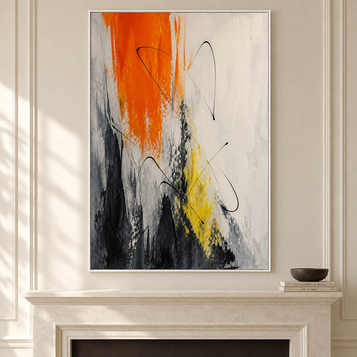 Vertical abstract artwork in orange, black, white, charcoal, and yellow, displayed beside or above a fireplace in a white frame.