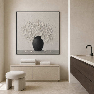 Textured white floral wall art displayed in a black and white bathroom.