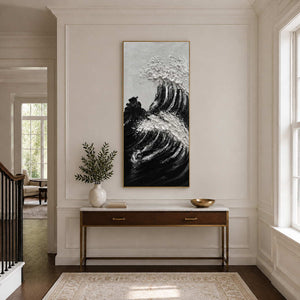 Gold framed coastal painting with curved black swells above a slim hallway console.