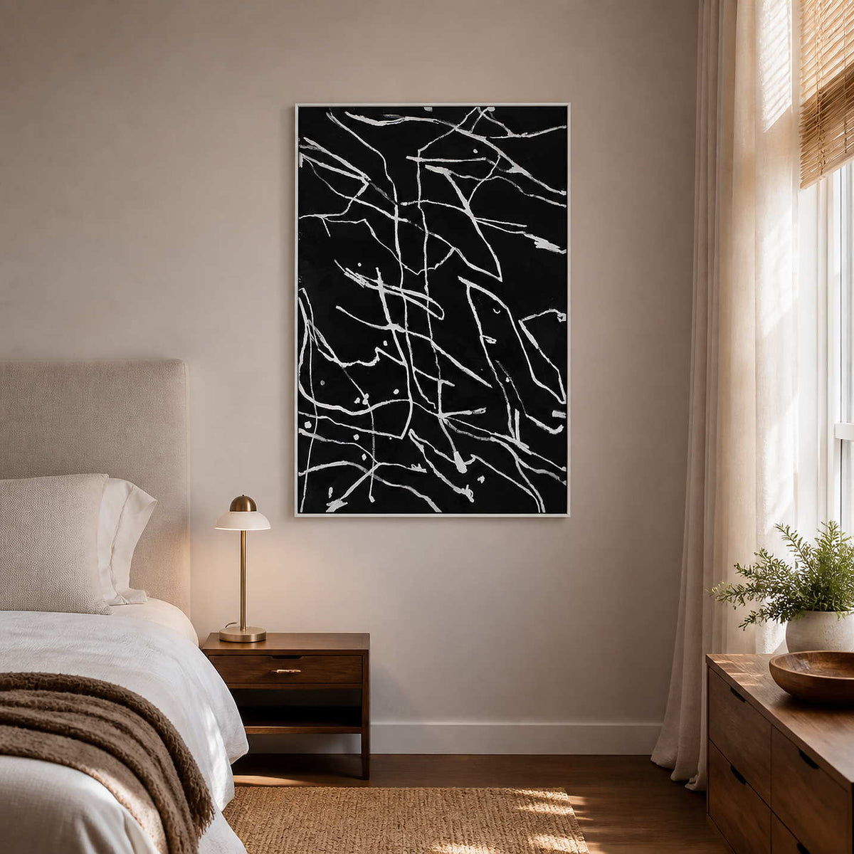White framed abstract line painting on a bedroom wall beside the bed.