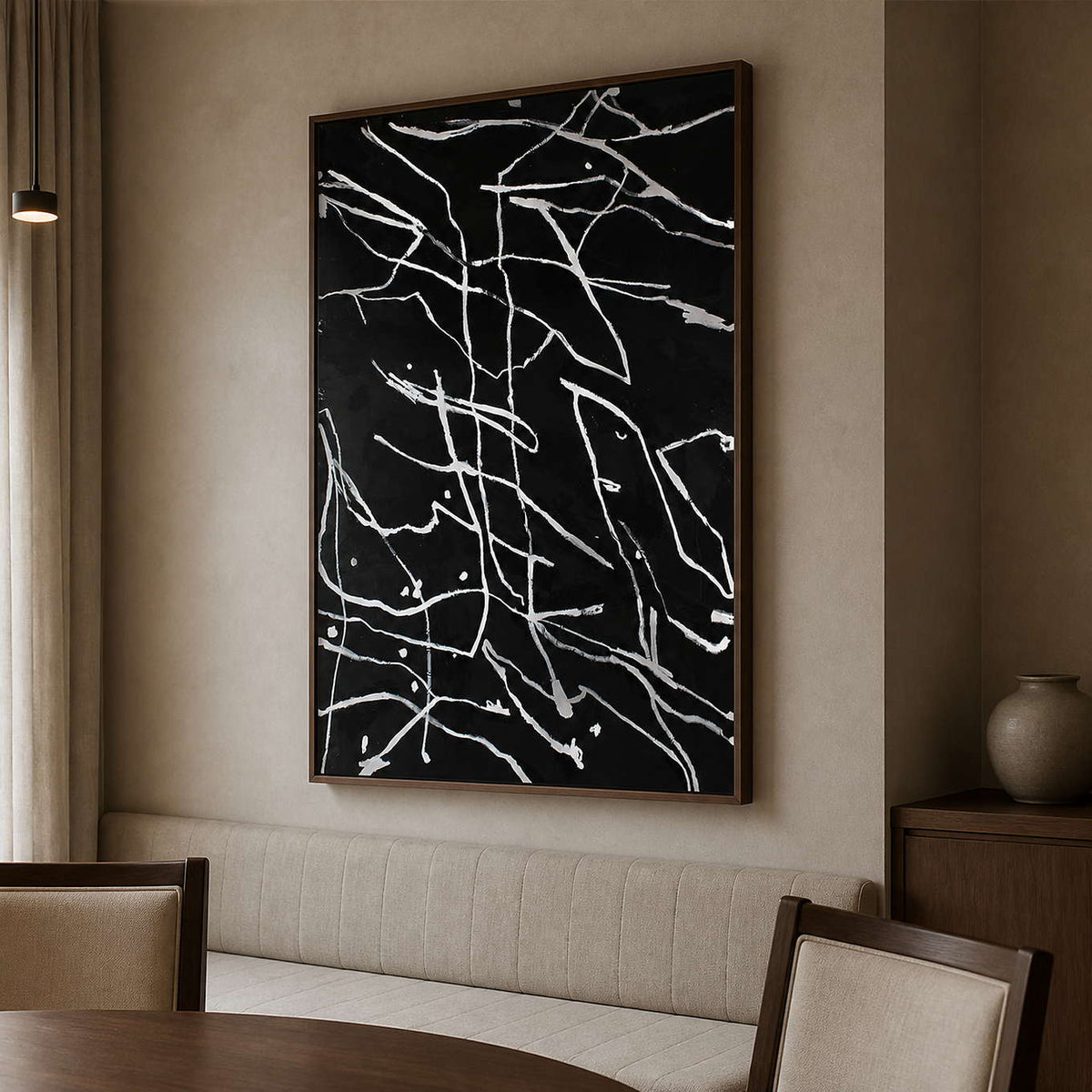 Wood framed black and white abstract painting beside a dining banquette.