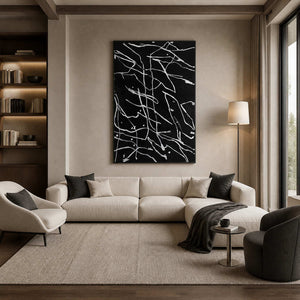 Black framed abstract painting with white branching lines above a cream sofa.