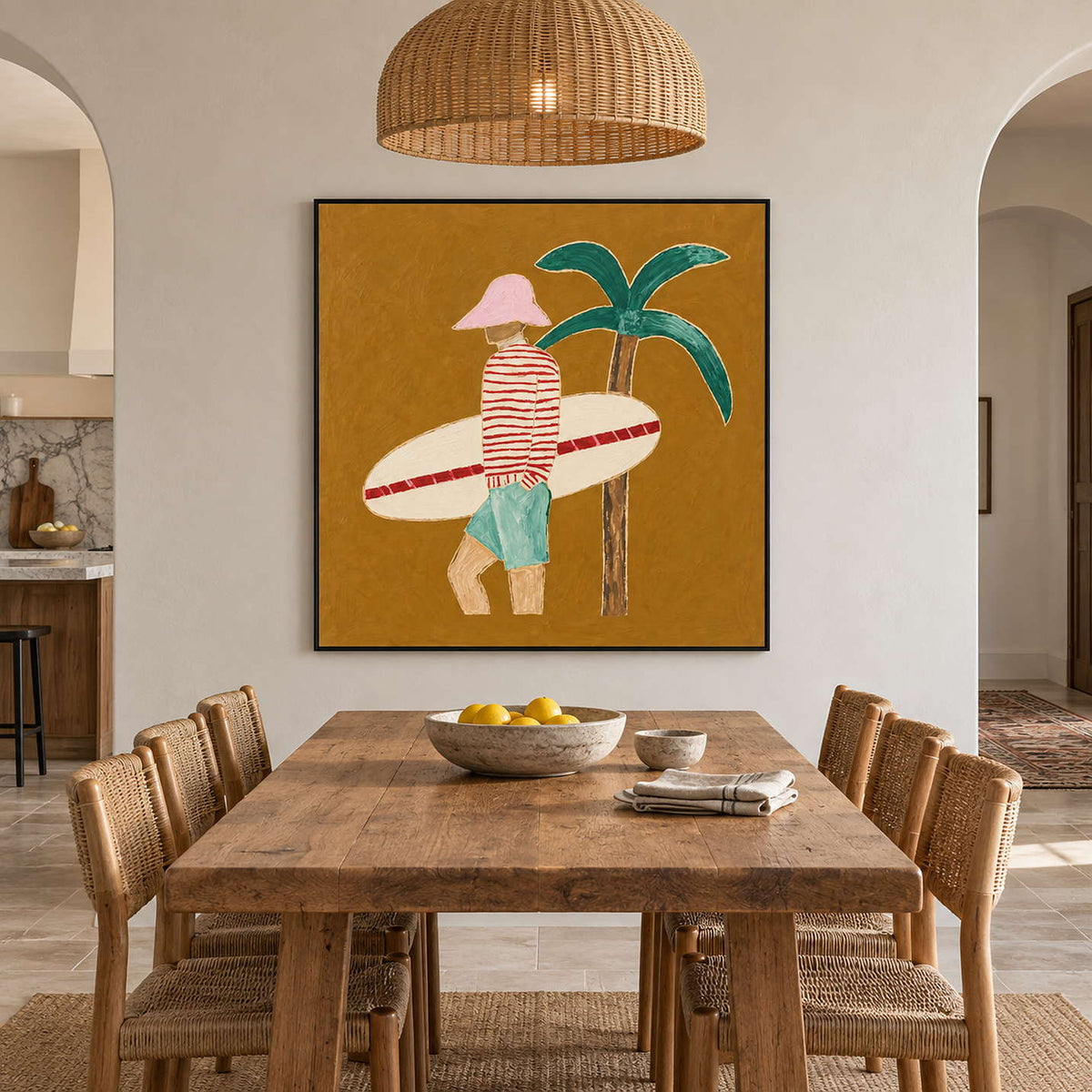Surfer and palm artwork above a rustic wood dining table with woven chairs and a woven pendant.