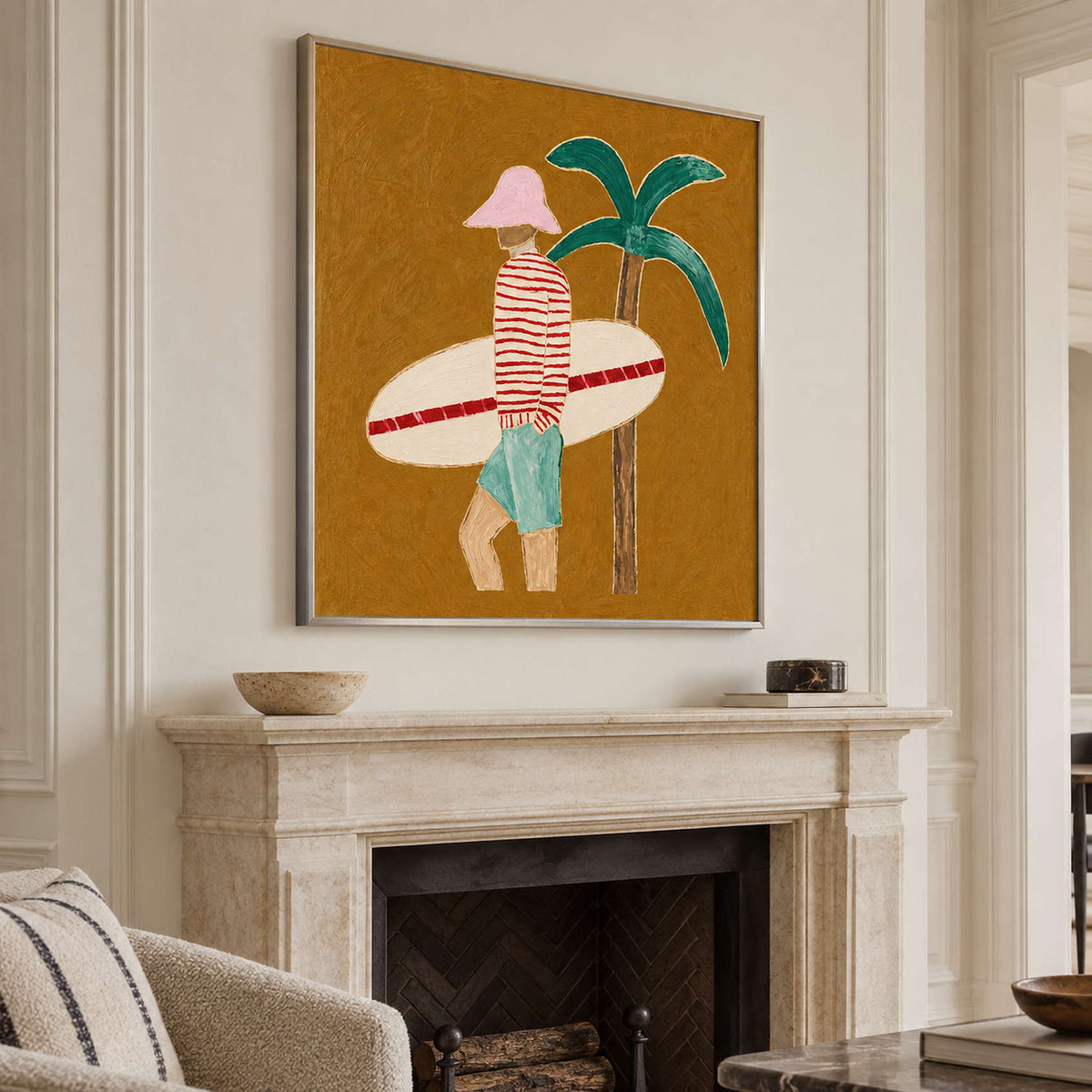 Angled view of the surfer and palm painting above a pale stone fireplace.