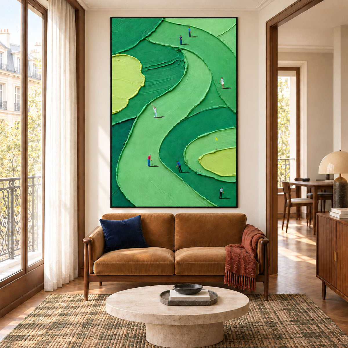 Small golfers on sweeping green fairways in a black frame, displayed above a sofa in a living room.