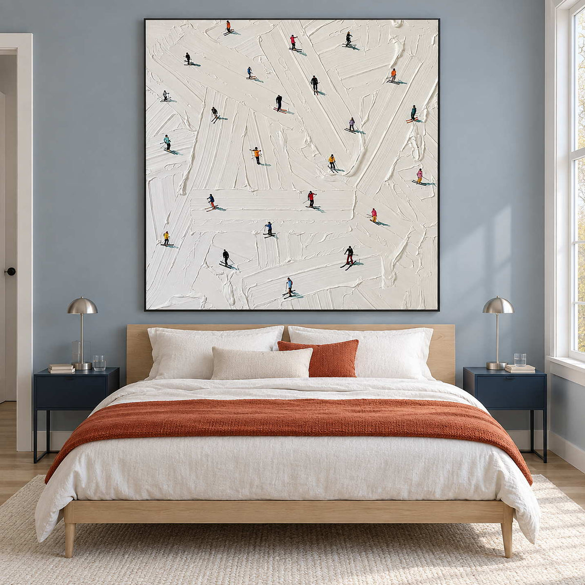 Square snow artwork above a bed with a rust-orange throw.