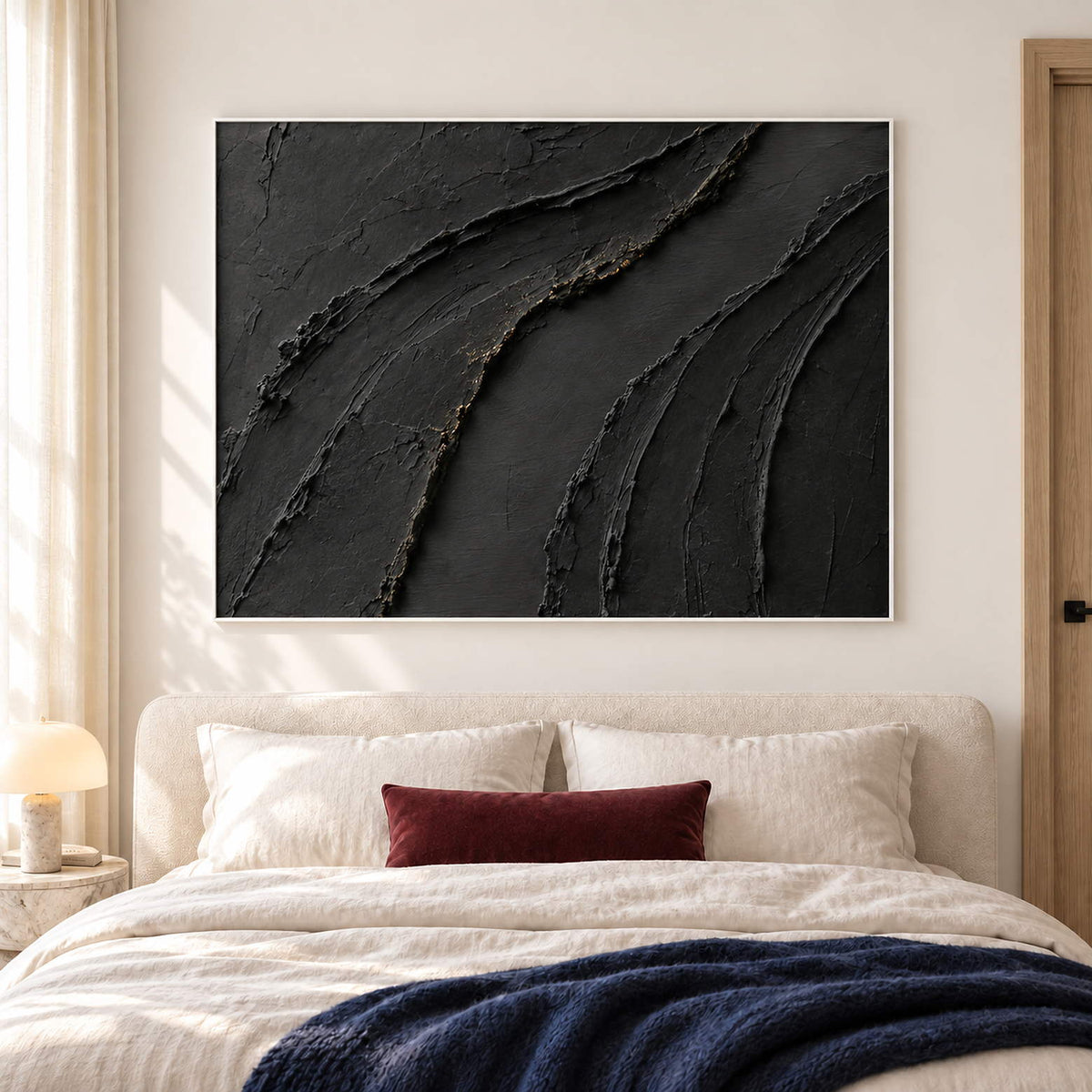 Sweeping raised black ridges with subtle gold accents in a white frame, displayed above a bed.