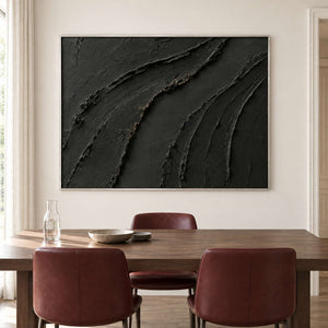 Sweeping raised black ridges with subtle gold accents in a silver frame, displayed above a dining table.