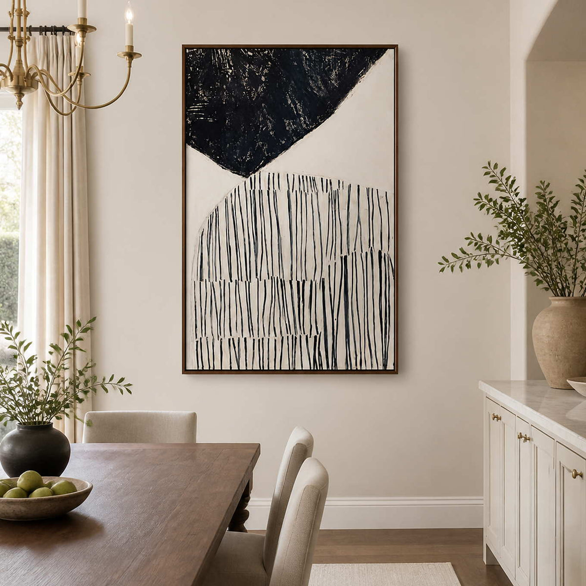 Wood framed black and ivory line painting beside a wooden dining table.