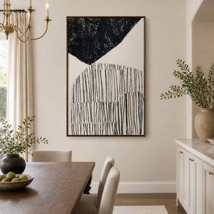 Wood framed black and ivory line painting beside a wooden dining table.