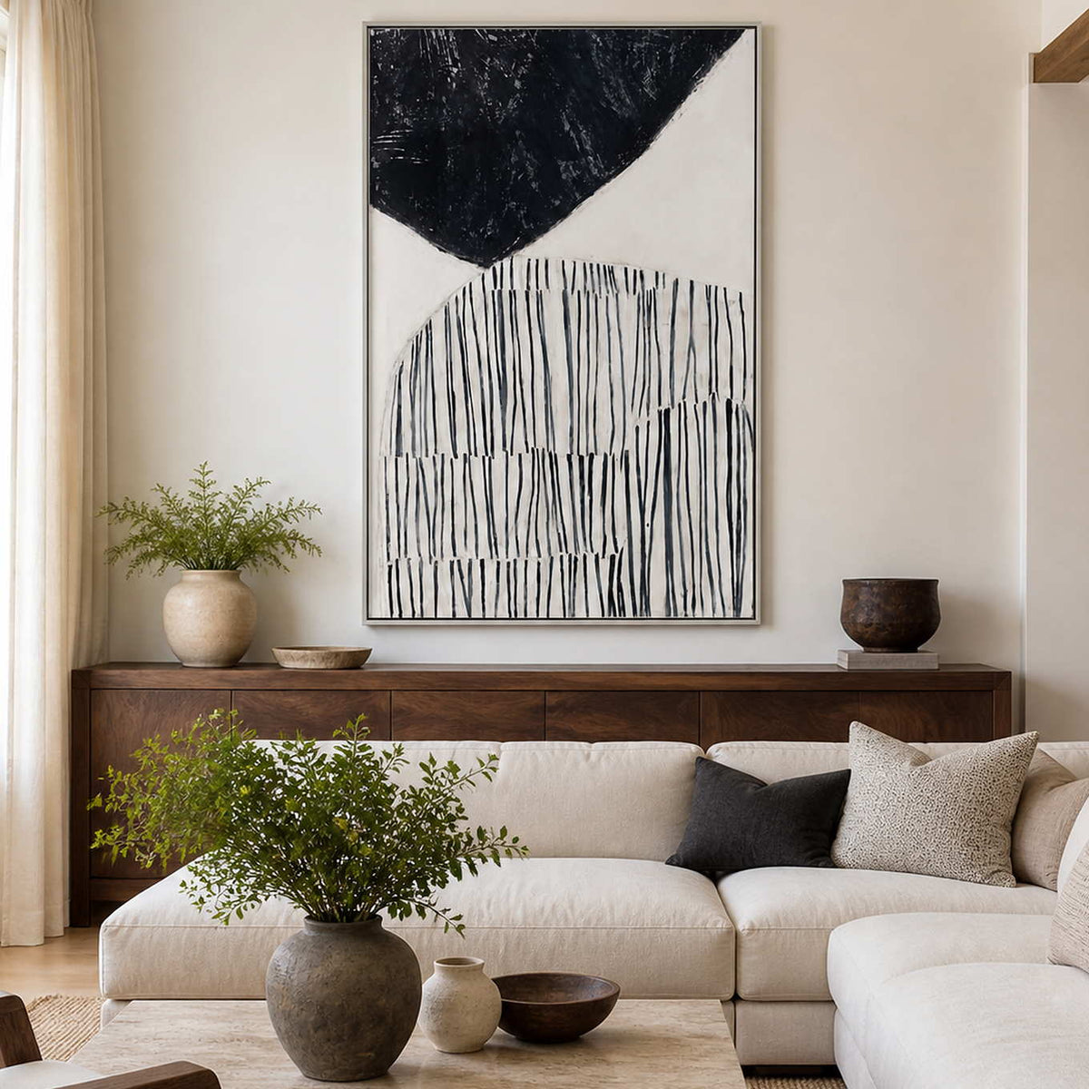 Silver framed vertical abstract painting above a console behind pale living room seating.