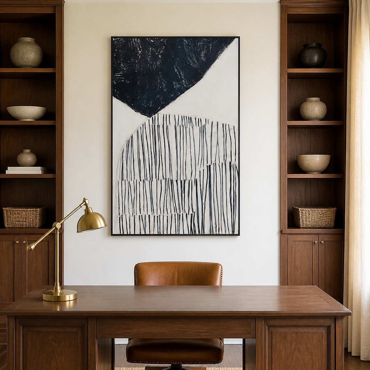 Black framed monochrome abstract artwork above a wooden desk between study shelves.