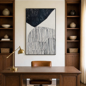 Black framed monochrome abstract artwork above a wooden desk between study shelves.