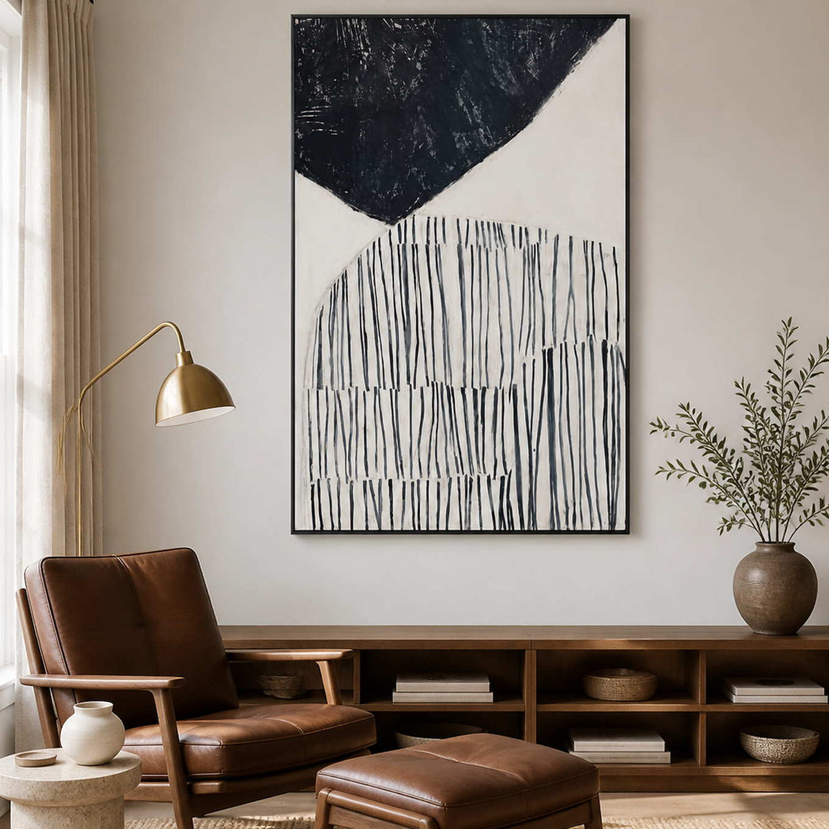 Black framed line painting above a low bookshelf beside a leather reading chair.