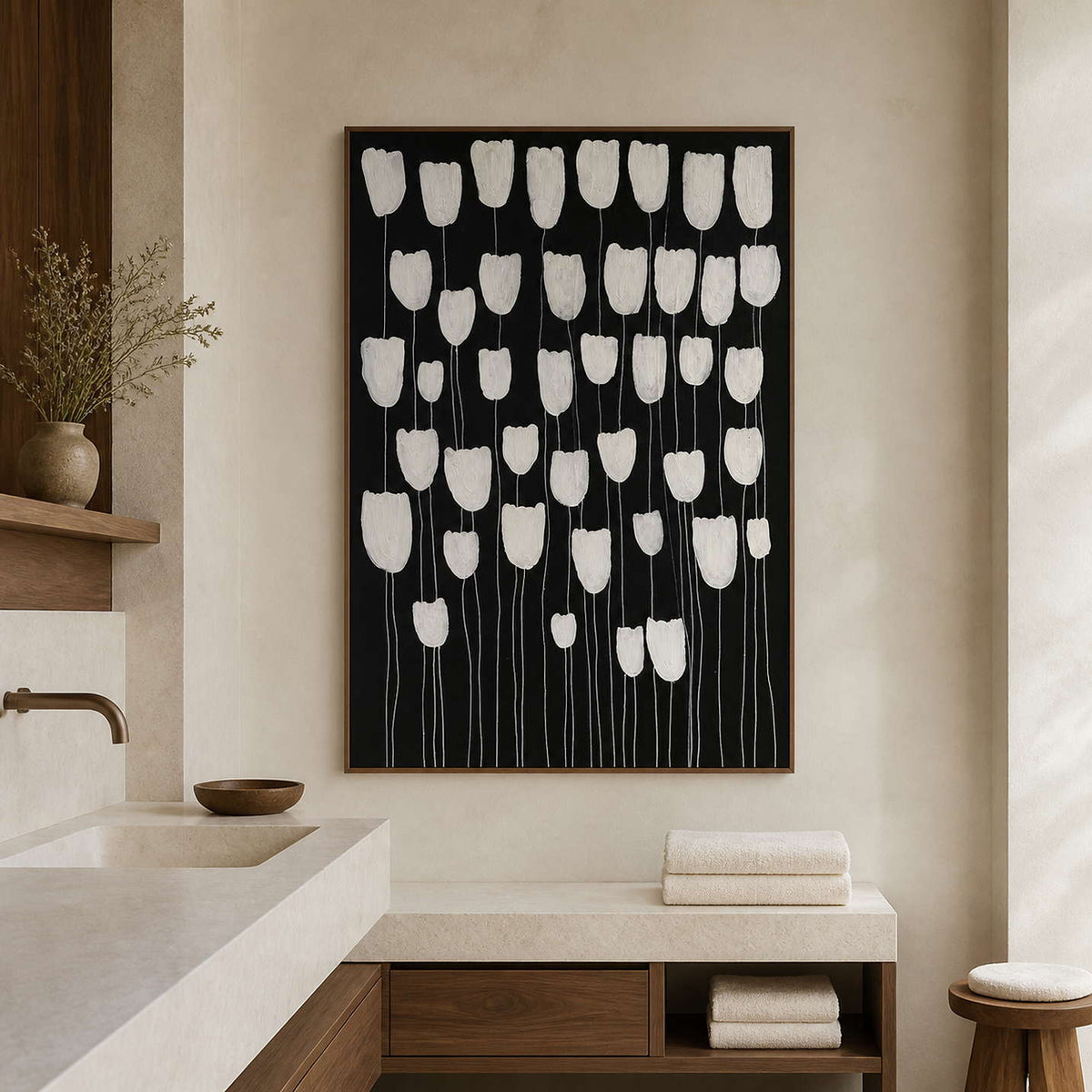 Wood framed white flower artwork against black beside a pale stone bathroom vanity.