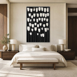 White framed black and white floral artwork above a softly upholstered bed.
