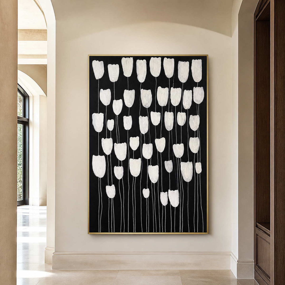 Gold framed white floral painting on a light wall in an arched hallway.