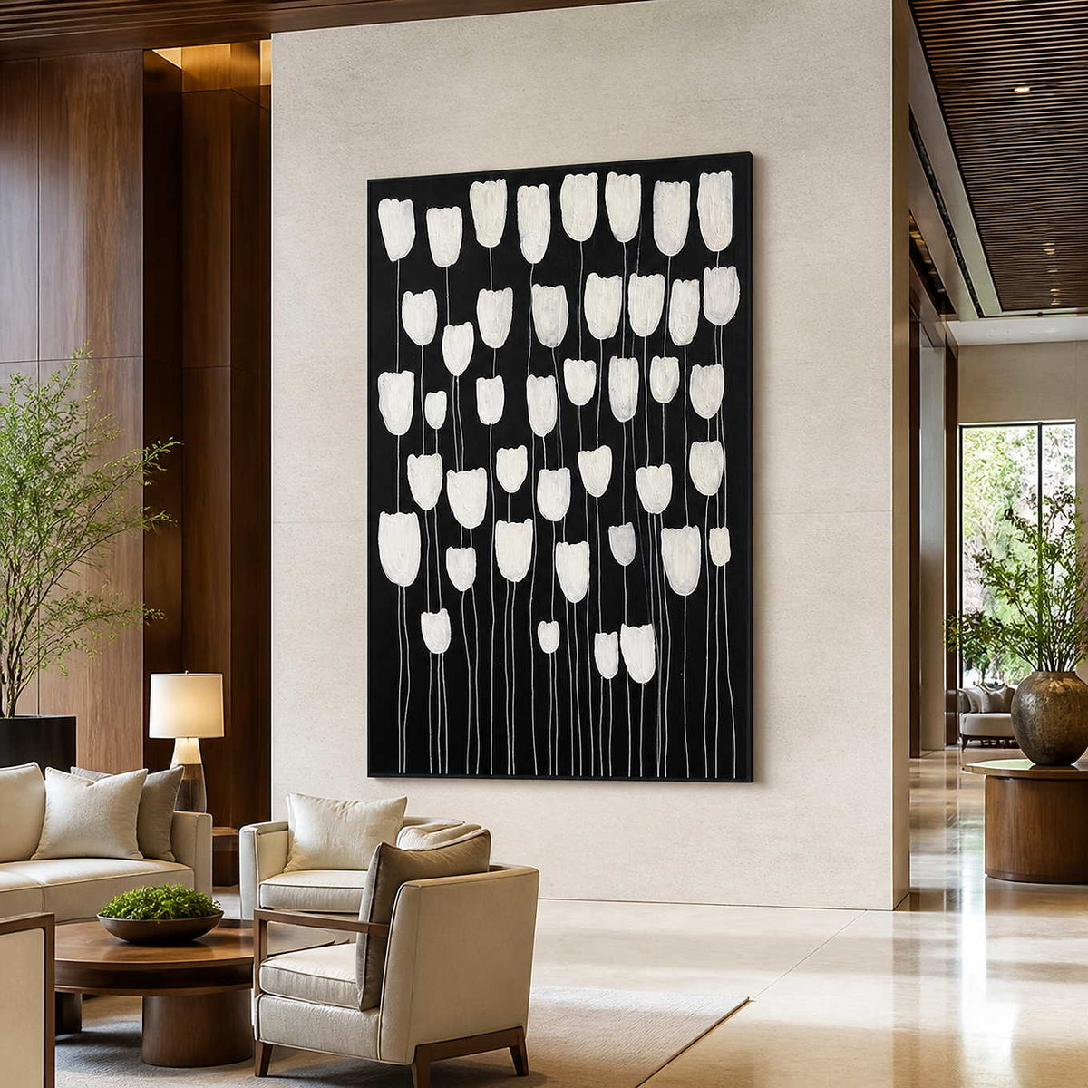 Black framed white floral painting above lounge chairs in a warm hotel lobby.