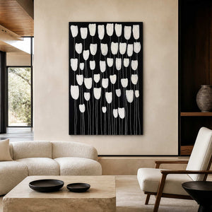 Frameless white floral artwork against black above cream seating in a contemporary living room.
