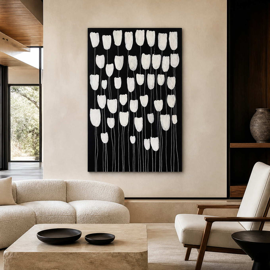 Frameless white floral artwork against black above cream seating in a contemporary living room.