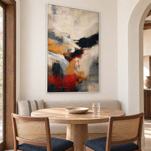 Ivory, ochre and red abstract strokes crossed by bold black bands in a white frame, displayed above a dining table.