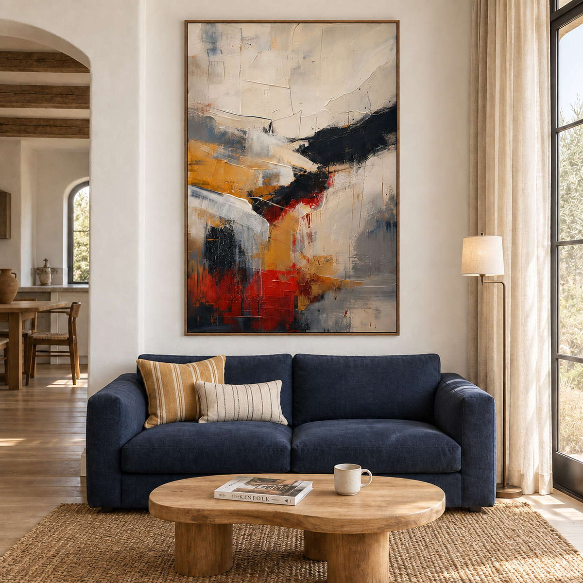 Ivory, ochre and red abstract strokes crossed by bold black bands in a brown wood frame, displayed above a sofa in a living room.