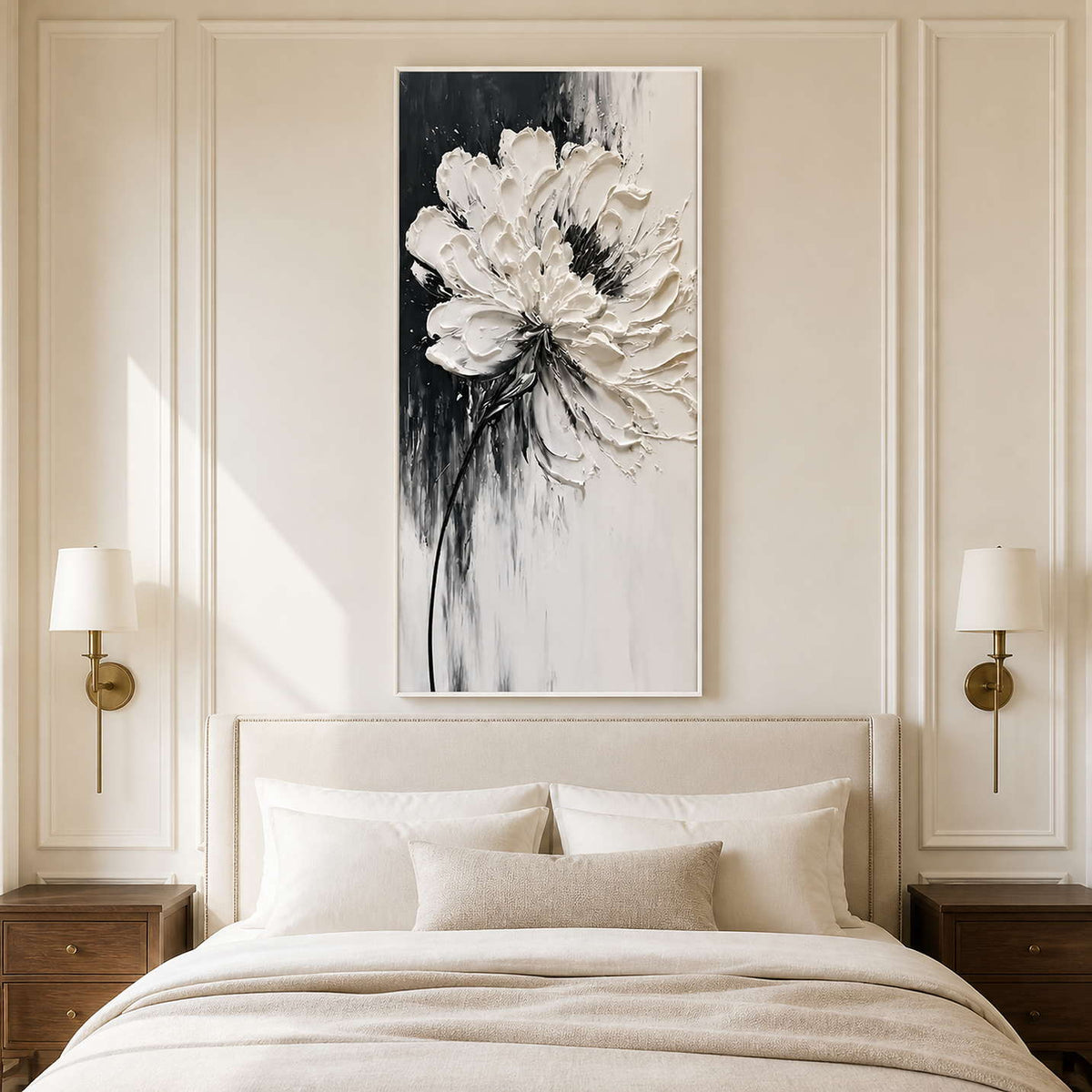 White framed tall floral artwork above a cream bed between brass wall lamps.