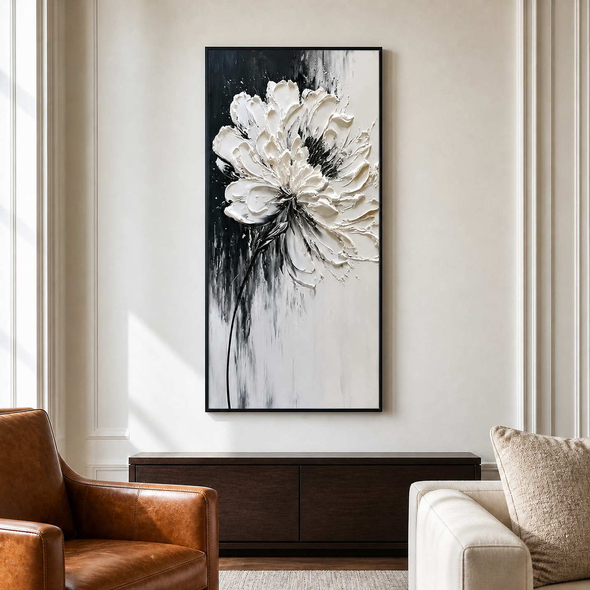 Black framed floral artwork between a leather armchair and a cream lounge sofa.