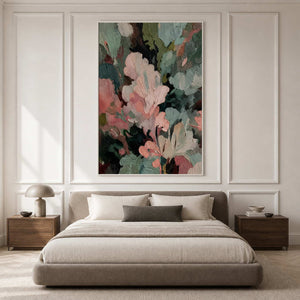 White framed pink and green abstract painting above a bed in a softly lit bedroom.