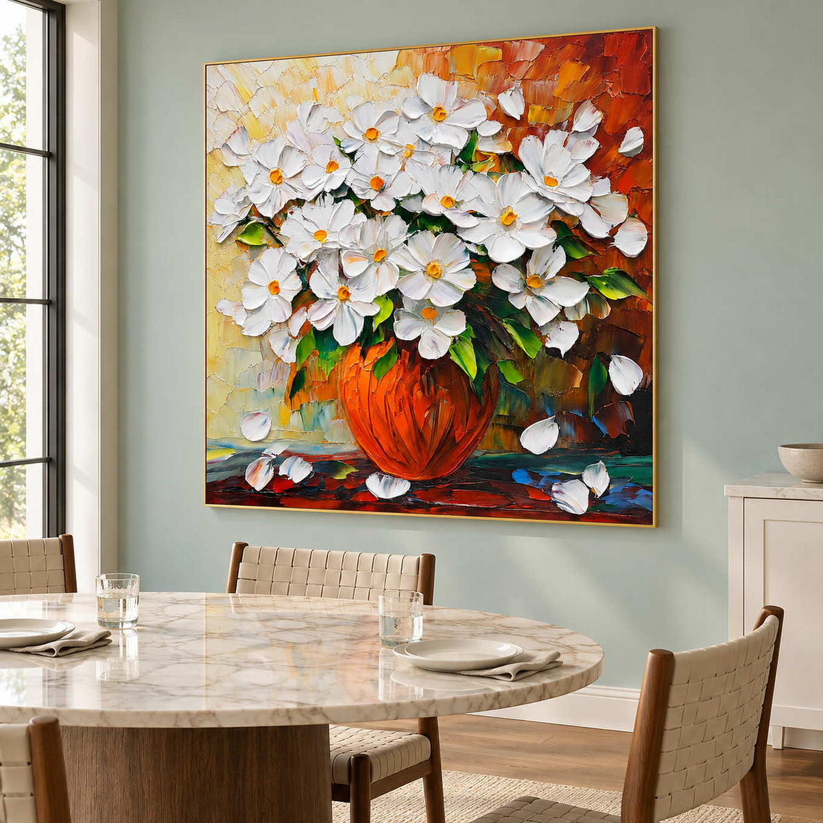 Orange-vase painting beside a pale round dining table and woven chairs.