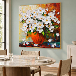 Orange-vase painting beside a pale round dining table and woven chairs.
