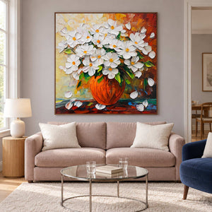 White-flower still life above a pale pink sofa.