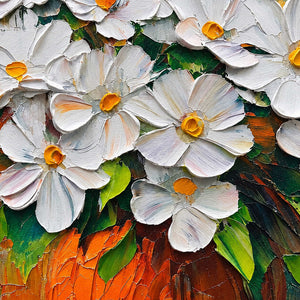 Detail of broad white petals, yellow centers, green leaves, and the orange vase.