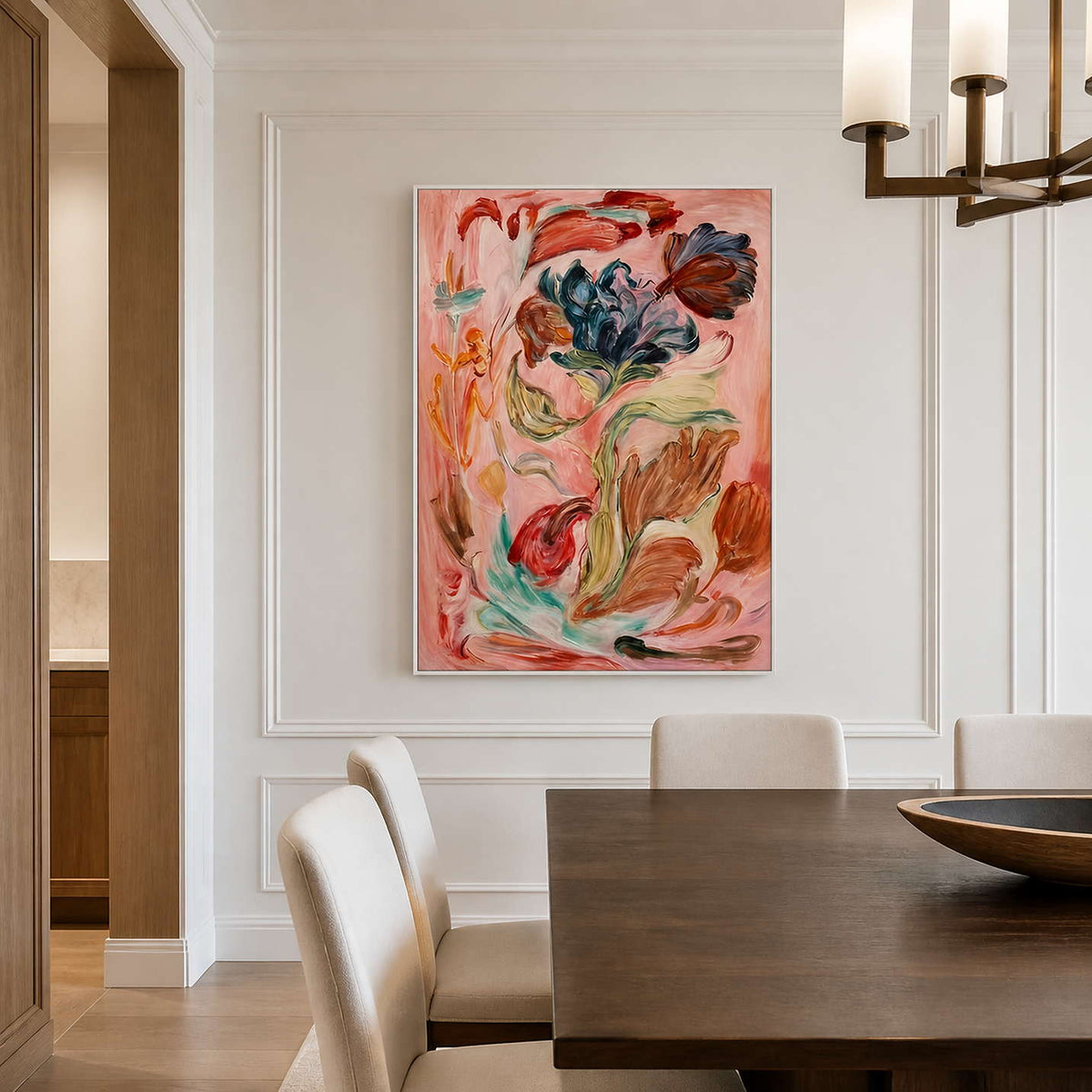 White framed expressive flowers above a dark dining table surrounded by cream chairs.